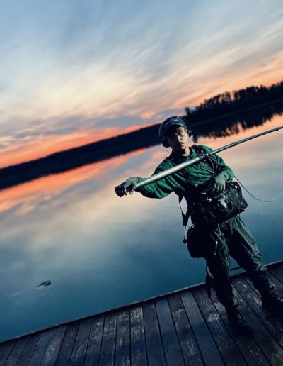 sound operator on movie set with boom microphone with lake